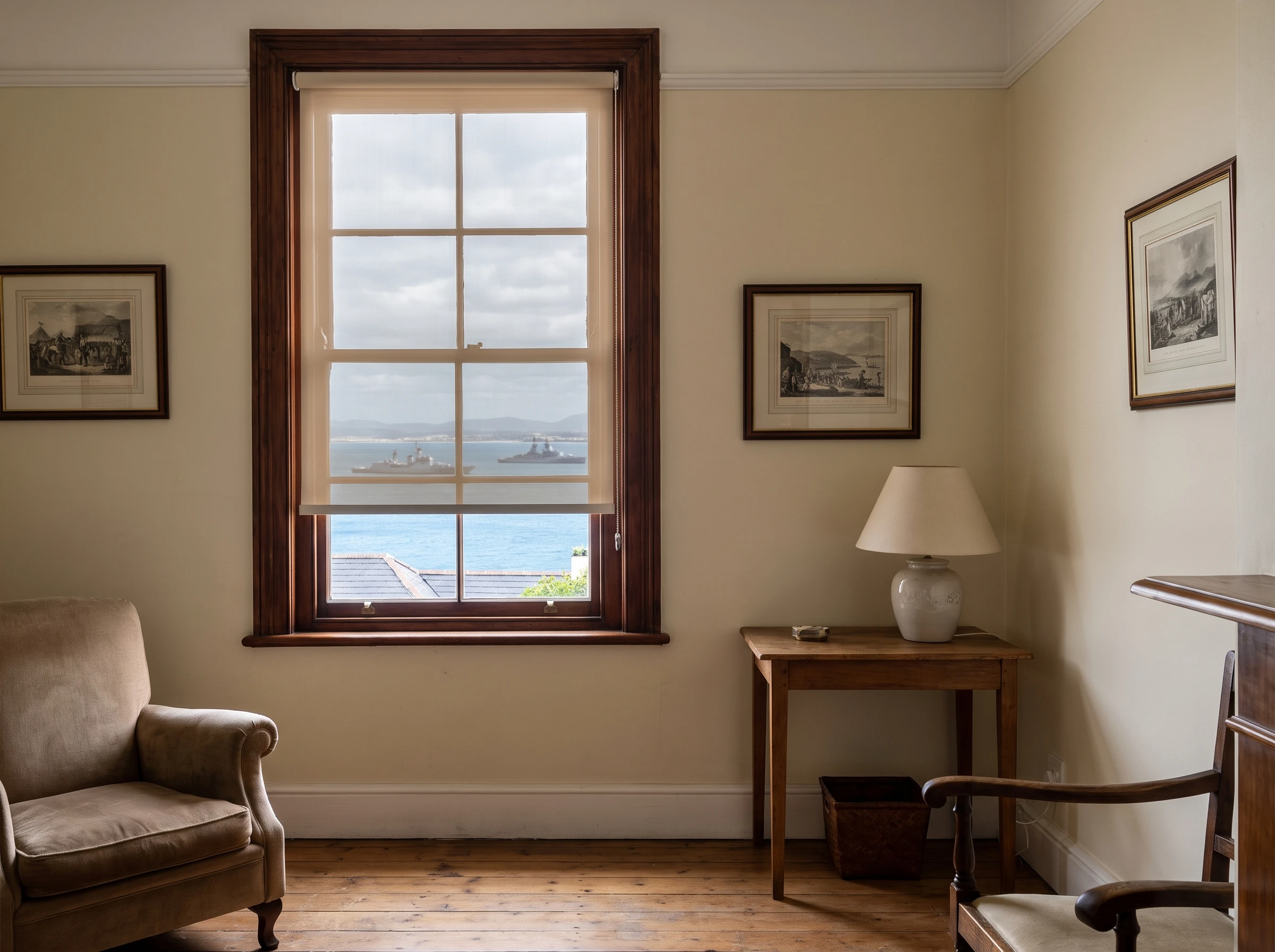 Sunscreen roller blind on a Victorian sash window in a Simon's Town home, naval vessels visible on False Bay through the glass