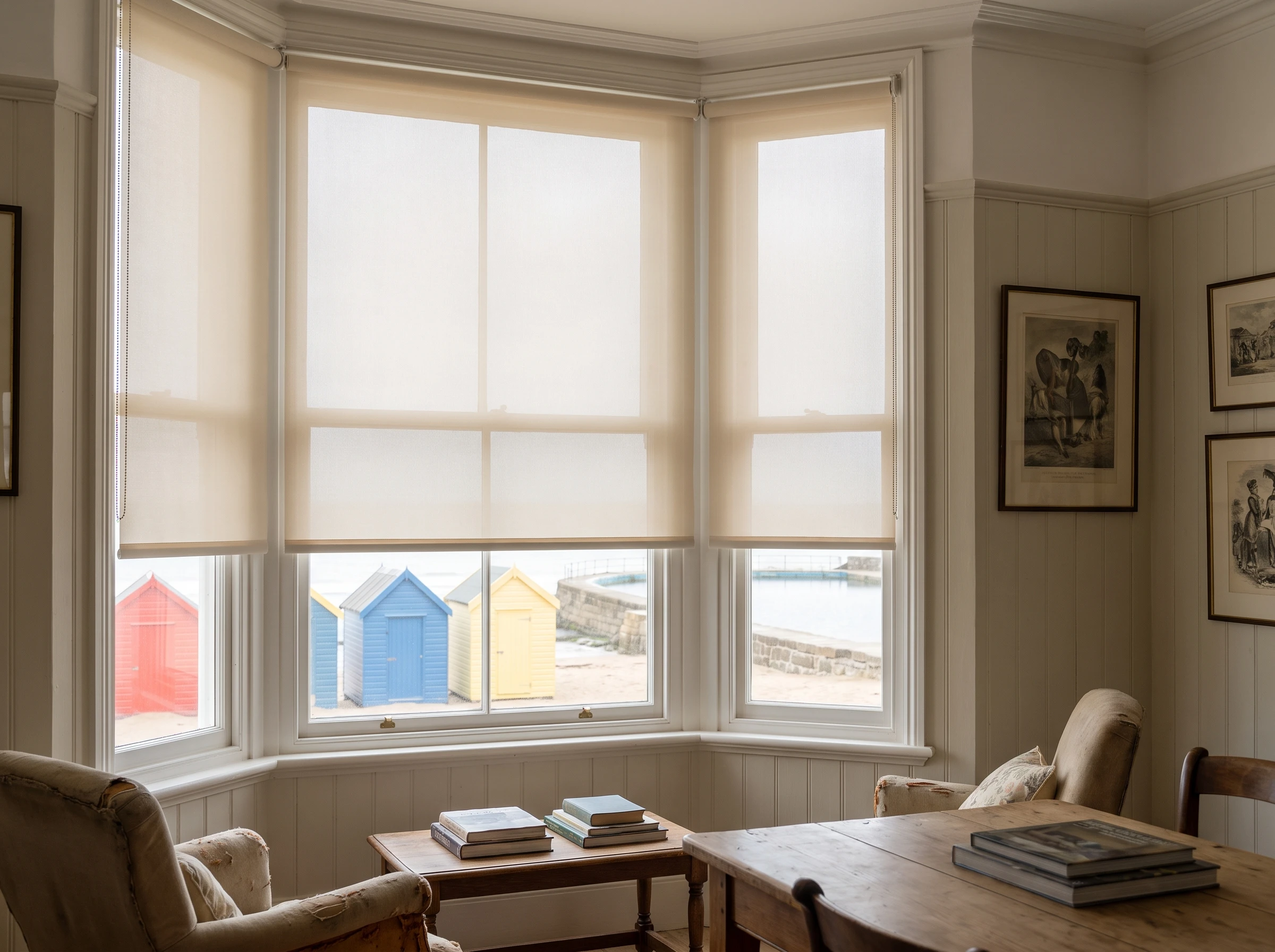 Sunscreen roller blinds on a Victorian bay window in a St James home, colourful bathing chalets and the tidal pool visible outside